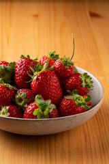 Fresh tasty Strawberries in a rustic bowl on a wooden table
