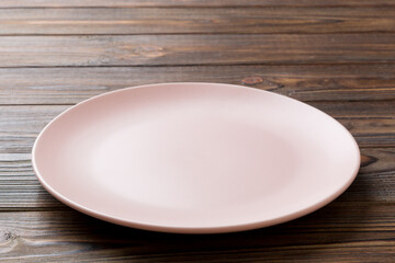 Perspective view of empty pink plate on wooden background. Empty space for your design