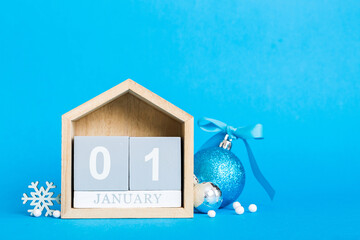 1 january. Christmas composition on colored background with a wooden calendar, with a gift box, toys, bauble copy space