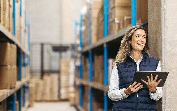 Female warehouse manager smiling while holding a digital tablet