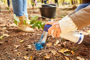 Naklejka premium Woman's hand sprays paint from spray can on tree pole