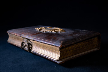altes antikes Buch mit Verzierung und Schließe aus Metall auf Ledereinband auf schwarzem Samt