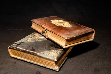 alte antike Bücher mit Verzierung und Schließe aus Metall auf Ledereinband auf schwarzem Samt