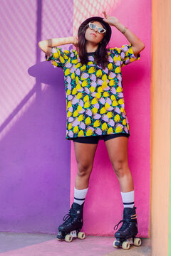 Woman wearing roller skates standing in front of multi colored wall