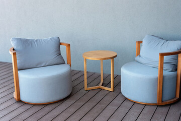 Close-up of cozy light blue upholstered chairs and a wooden table. Modern interior. Furniture for a summer residence. Soft selective focus.