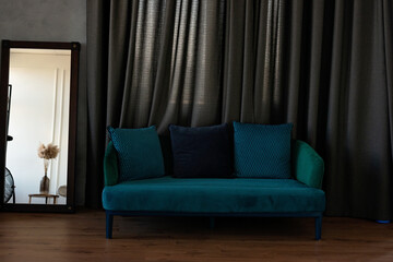 Stylish comfortable blue velor sofa with pillows in a modern interior. Soft selective focus.