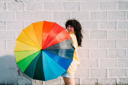 Happy woman spinning multi colored umbrella on sunny day