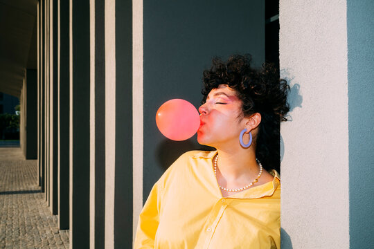 Woman with eyes closed blowing bubble gum on sunny day