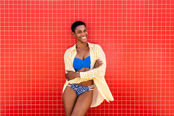 Happy woman with arms crossed leaning on red wall