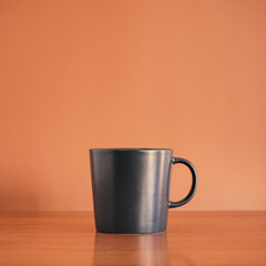 Black ceramic coffee cup on wood table with brown background