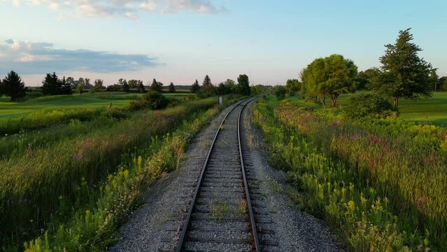 Drone flight along railroad track through scenic lush green countryside