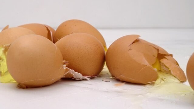Brown eggs drop on counter top, shells crack and spill in slow motion