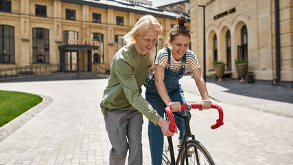 Guy teach teen girlfriend riding bicycle in city