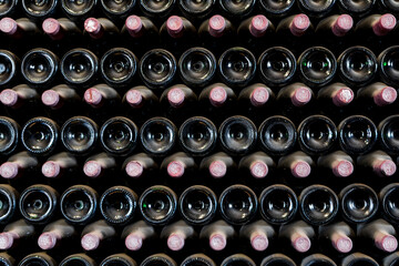 Many bottles in a row stacked on a winery shelf