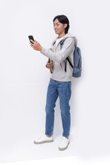 Full body young asian student in hoodie, jeans with folder and mobile phone with backpack on white background