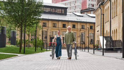 Front view of young couple walking with bicycles