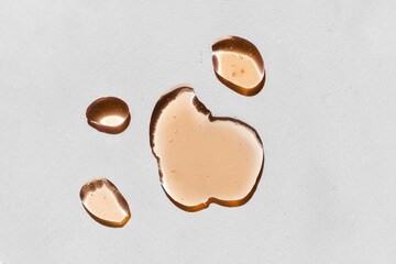 Orange cosmetics gel, serum or peeling drop isolated on white background. Oily slime with air bubbles in the sunlight. High contrast trendy beauty pattern. Health protection and self-care concept.