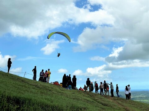 Group of people on a hill watching a para-glider
