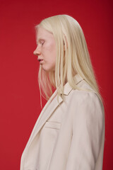 Side view of albino young girl with white hair standing against red background - obrazy, fototapety, plakaty