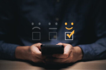 Businessman using smartphone for select smiley face icon for client evaluation and customer...
