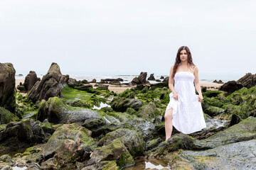 Fototapeta na wymiar woman with white dress among the rocks on the beach