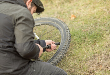 a young man pumps up the tires of a mountain bike with a pump on the street. a young man pumps up the tires of a mountain bike with a pump on the street. wheel and hand close-up