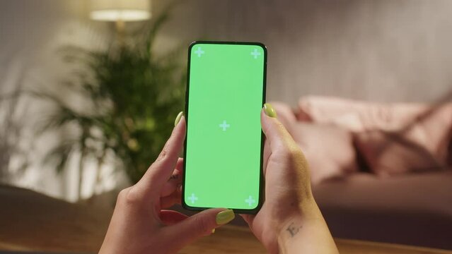 Touching Tapping on Center Screen. Handheld Camera: Point of View of Woman at Phone with Green Screen for Copy Space. Chromakey Mock Up With Tracking Markers. Close Up. Girl is Surfing Content