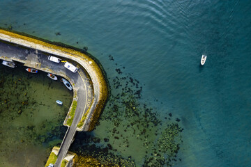 Camper vans on a small pier and fishing boat in the ocean. Top down aerial view. Travel and holiday...