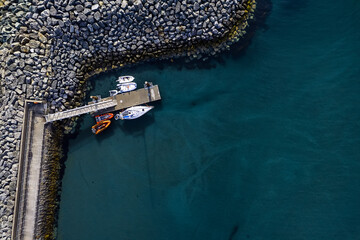 Small boats and sailing yacht by a pier. Aerial top down view. Water sport and hobby concept. Copy space.