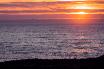 Sunset sky over the ocean water surface. Warm and cool tone. Calm and peaceful mood. Nature background. Ocean waves and clouds.