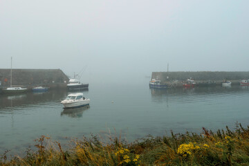 Small boat in a harbor morning fog in the background. Cool tone and mood. Transportation and travel theme.