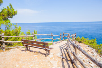 Fototapeta na wymiar Amazing view of sea nature environment from viewpoint with empty wooden bench. Turquoise color of water. Clear blue sky. Summer landscape.