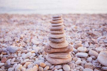 Fototapeta na wymiar Balanced harmony stones pyramid at beach coast. Summer sunset light. Zen meditation concept.