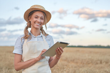 Fototapeta premium Woman farmer straw hat smart farming standing farmland smiling using digital tablet Female agronomist specialist research monitoring analysis data agribusiness