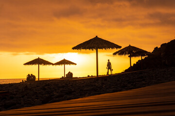 Orange sunset on the umbrellas at Ponta do Sol beach, Madeira. Portugal