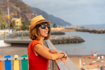 Praia da Calheta in summer, young tourist girl in red dress on the beach, Madeira. Portugal