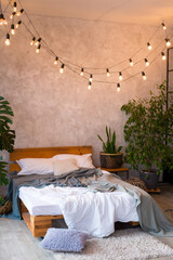 Cozy bedroom area at luxury studio apartment with a free layout in a loft style with big panoramic window and green plant.