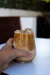 Woman hold glass of a iced coffee with cream milk.