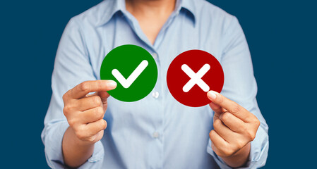 Close-up of hands holding two papers circle shape with a checkmark and cross while standing on a...