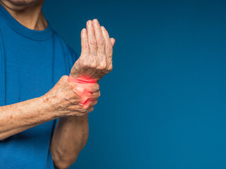 Hands senior woman suffering from wrist pain while standing on a blue background