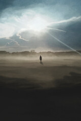 lonely man walks towards the sun's rays that illuminate the surrounding landscape