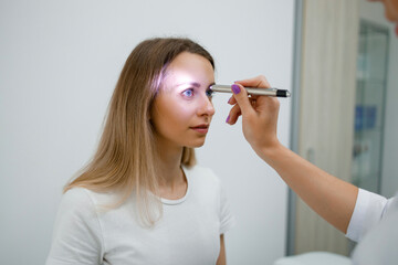 Obraz premium Neurologist doctor checking pupillary response to light with flashlight