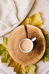 Autumn mood: cup of coffee, warm wool sweater and yellow leaves. Seasonal breakfast, morning coffee. The concept of home comfort and cozy atmosphere.