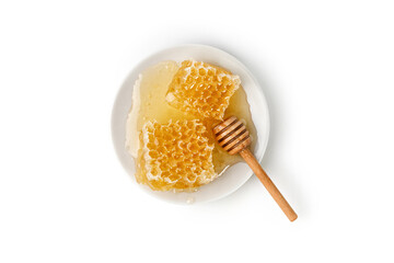 Honeycomb with honey on a white plate with honey dipper isolated on white background.