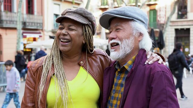 Multiracial senior couple having fun together in the city - Diverse elderly people and travel concept