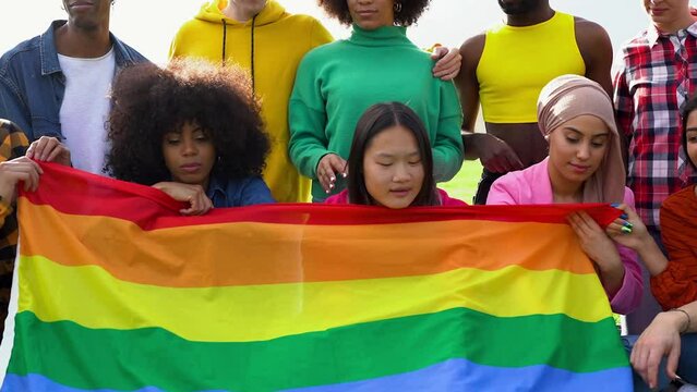 Group of happy diverse people having fun outdoor with LGBT rianbow flag
