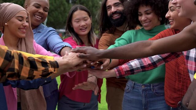Group of young multiethnic people stacking hands in the city