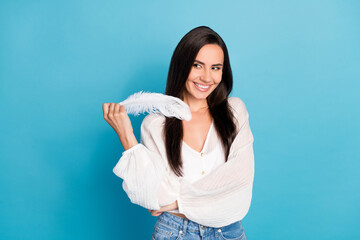 Photo of funny adorable young lady wear white top holding fluffy feather looking empty space...