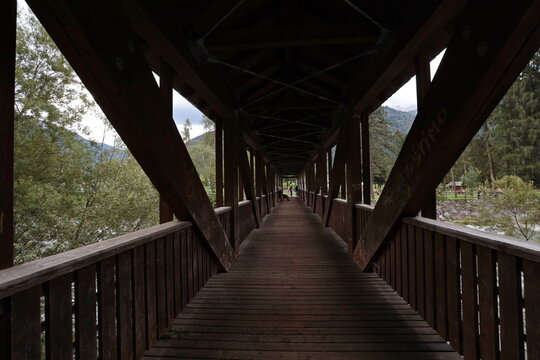 Pinzolo, Trento, Italy - August 20, 2022: The wooden bridge across the Sarca River in Pinzolo, Trentino, Italy.