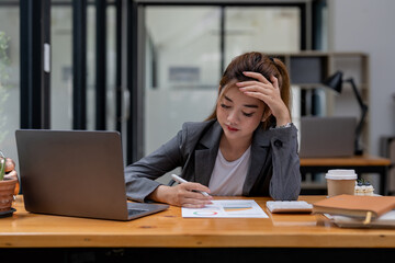 Stressed business woman working from home on laptop looking worried, tired and overwhelmed.